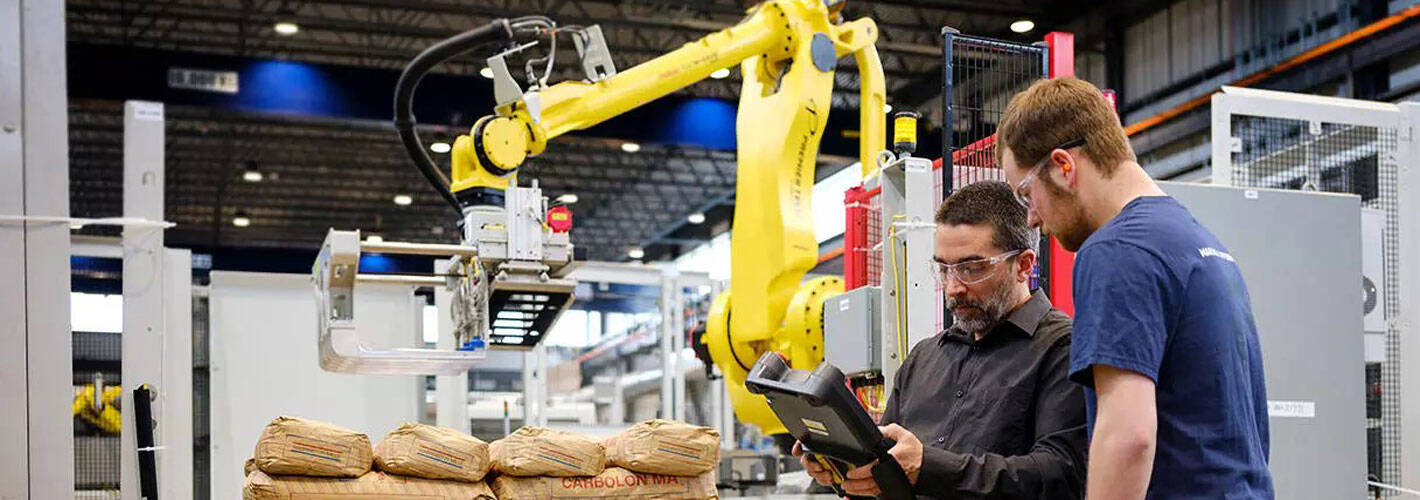 Premier tech team members by an industrial palletizer