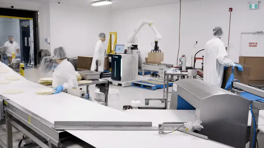 Bakery team members working alongside a TOMA™ palletizer in a collaborative automated packaging line