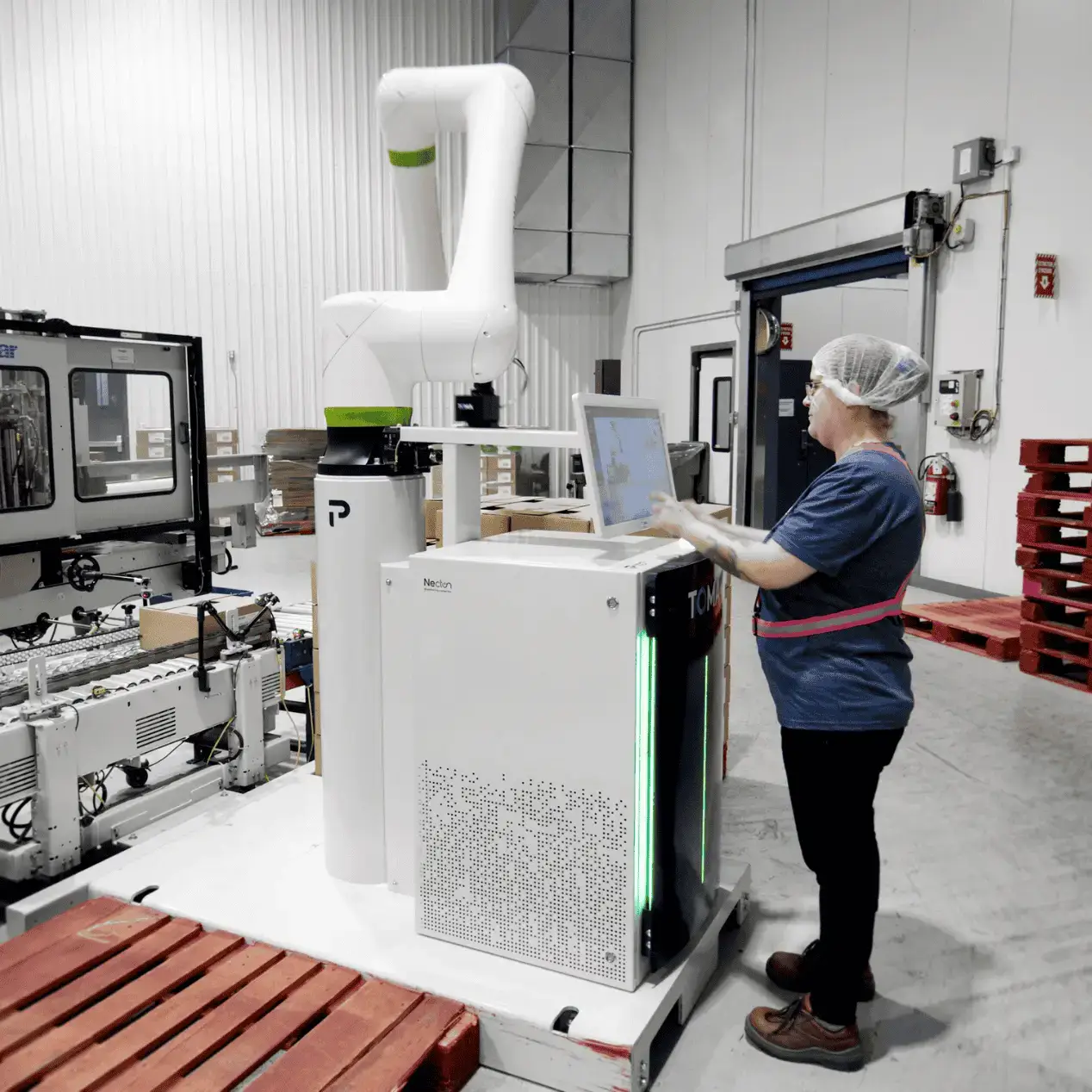 Operator supervising a TOMA cobot palletizer that takes over heavy, repetitive tasks to reduce labor shortages on the line
